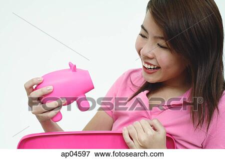 Stock Photo - Woman dressed in pink, holding pink piggy bank. Fotosearch