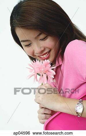 Stock Photograph - Woman dressed in pink, holding pink flower. Fotosearch