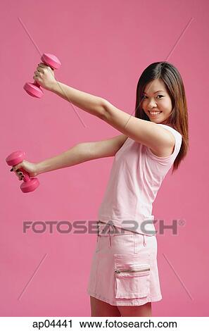 Stock Image - Woman dressed in pink, lifting dumbbell. Fotosearch
