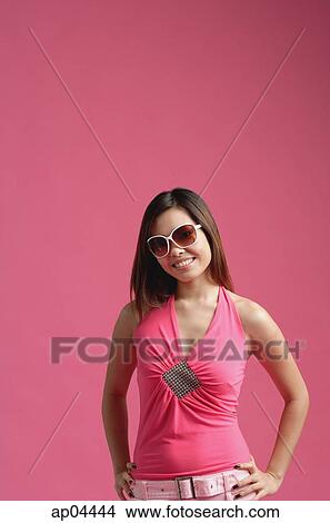 Woman dressed in pink, wearing sunglasses, standing against pink background, View Large Photo Image Picture - Woman dressed in pink, wearing sunglasses, standing against pink background,. Fotosearch