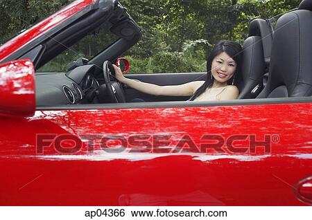 Woman driving red sports car, looking at camera View Large Photo Image Stock Photograph - Woman driving red sports car, looking at camera. Fotosearch