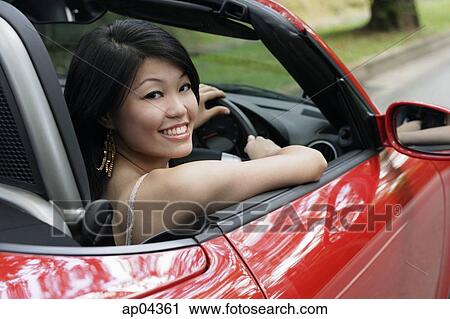 Woman driving red sports car, turning to smile at camera View Large Photo Image Stock Image - Woman driving red sports car, turning to smile at camera. Fotosearch