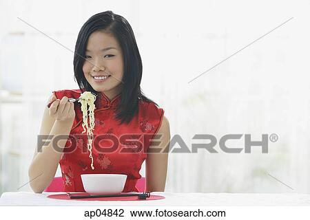 Stock Image - Woman eating bowl of noodles. Fotosearch