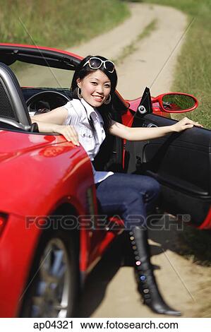 Woman getting out of red sports car, smiling at camera View Large Photo Image Stock Image - Woman getting out of red sports car, smiling at camera. Fotosearch