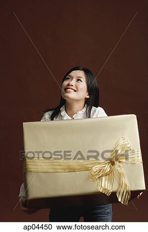 Woman holding gold gift wrapped box View Large Photo Image Stock Image - Woman holding gold gift wrapped box. Fotosearch