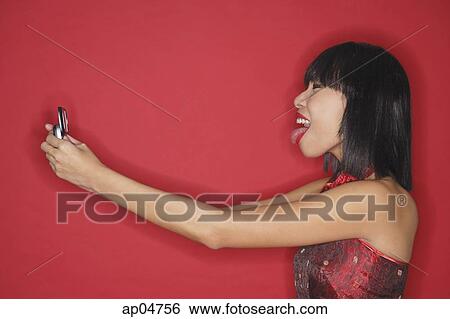 Woman holding mobile phone, sticking tongue out View Large Photo Image Stock Photograph - Woman holding mobile phone, sticking tongue out. Fotosearch