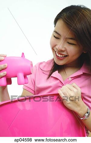 Stock Photo - Woman holding pink piggy bank. Fotosearch