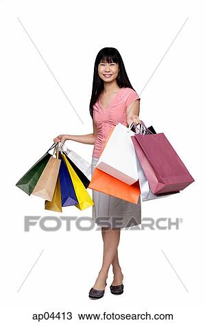 Stock Image - Woman holding shopping bags, smiling at camera. Fotosearch