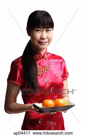 Stock Photo - Woman in Cheongsam, holding plate with two oranges. Fotosearch