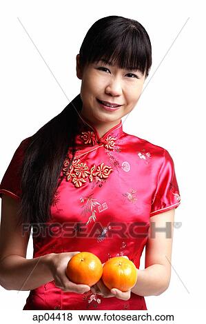 Stock Photo - Woman in Cheongsam, holding two oranges. Fotosearch