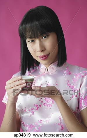Stock Photo - Woman in pink cheongsam, holding Chinese tea cup. Fotosearch