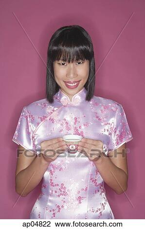Stock Image - Woman in pink cheongsam, with Chinese tea cup, portrait. Fotosearch