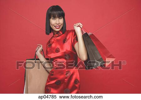 Stock Photography - Woman in red cheongsam with shopping bags. Fotosearch