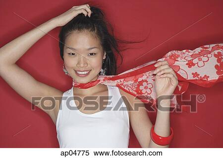 Stock Photography - Woman in white top and scarf, looking at camera, hand on head. Fotosearch