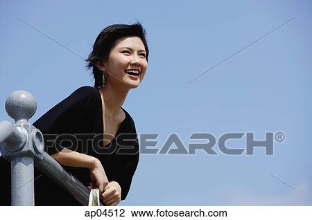 Woman leaning on railing, smiling, looking away View Large Photo Image Stock Image - Woman leaning on railing, smiling, looking away. Fotosearch