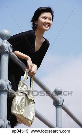 Woman leaning on railing, smiling, looking away View Large Photo Image Stock Image - Woman leaning on railing, smiling, looking away. Fotosearch