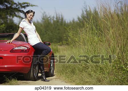 Woman leaning on red sports car, smiling at camera View Large Photo Image Stock Photo - Woman leaning on red sports car, smiling at camera. Fotosearch
