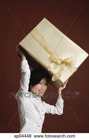 Stock Photo - Woman lifting big gift wrapped box. Fotosearch