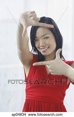 Picture - Woman making a finger frame, smiling at camera. Fotosearch