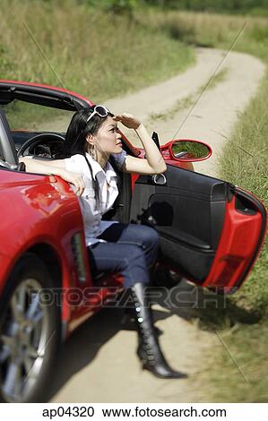 Woman sitting in red sports car, shielding eyes View Large Photo Image Stock Image - Woman sitting in red sports car, shielding eyes. Fotosearch