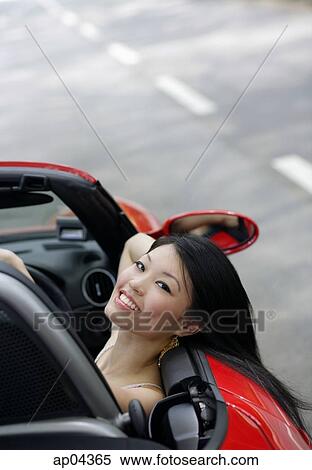 Woman sitting in red sports car, leaning head on door, smiling at camera View Large Photo Image Stock Photography - Woman sitting in red sports car, leaning head on door, smiling at camera. Fotosearch