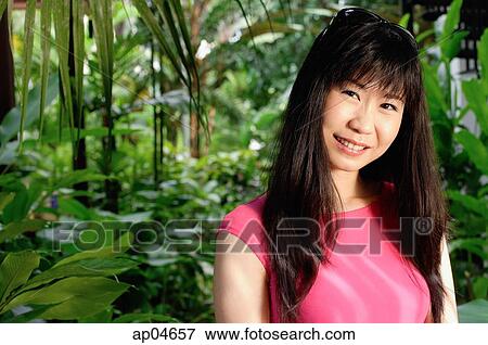 Woman standing in garden, smiling at camera View Large Photo Image Stock Photo - Woman standing in garden, smiling at camera. Fotosearch