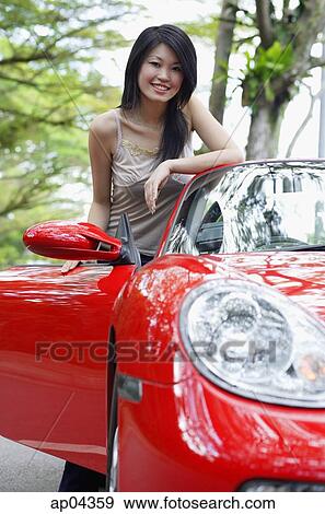 Woman standing next to red sports car View Large Photo Image Stock Photo - Woman standing next to red sports car. Fotosearch