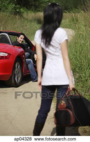 Woman standing on side of road, looking at man in red sports car View Large Photo Image Stock Photo - Woman standing on side of road, looking at man in red sports car. Fotosearch