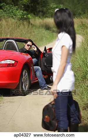 Woman standing on side of road, carrying bag, looking at man in red sports car View Large Photo Image Stock Photo - Woman standing on side of road, carrying bag, looking at man in red sports car. Fotosearch