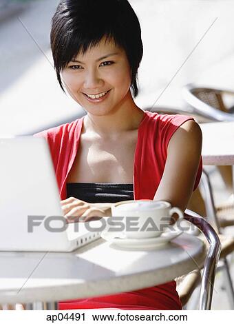 Stock Image - Woman using laptop at cafe. Fotosearch