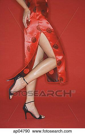 Stock Image - Woman wearing cheongsam and high heels, standing on one leg. Fotosearch