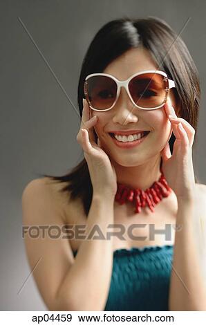 Stock Photo - Woman wearing large sunglasses, smiling at camera. Fotosearch