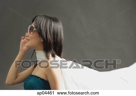 Stock Image - Woman wearing large sunglasses, tube top and scarf, looking away. Fotosearch