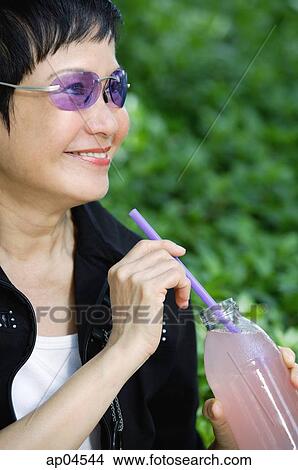 Picture - Woman with bottled drink and straw, looking away. Fotosearch