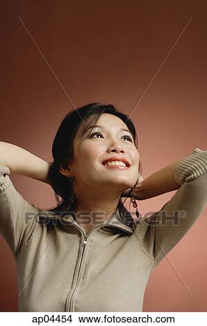 Picture - Woman with hands behind head, looking up. Fotosearch