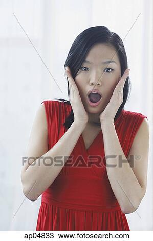 Stock Image - Woman with hands on either side of face, mouth open. Fotosearch