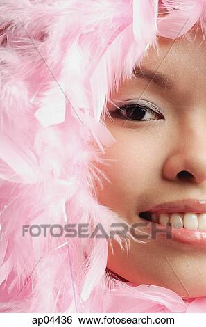 Stock Photograph - Woman with pink feathers around her face, cropped image. Fotosearch