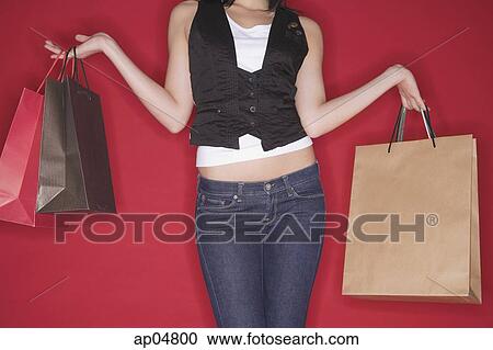 Stock Image - Woman with shopping bags, mid-section. Fotosearch