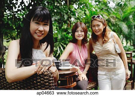 Stock Image - Women at outdoor garden cafe, looking at camera, portrait. Fotosearch