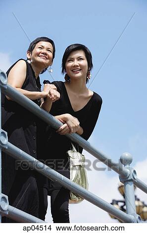 Women leaning on railing, smiling, looking away View Large Photo Image Picture - Women leaning on railing, smiling, looking away. Fotosearch