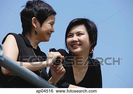 Women side by side, smiling, looking away View Large Photo Image Stock Photograph - Women side by side, smiling, looking away. Fotosearch