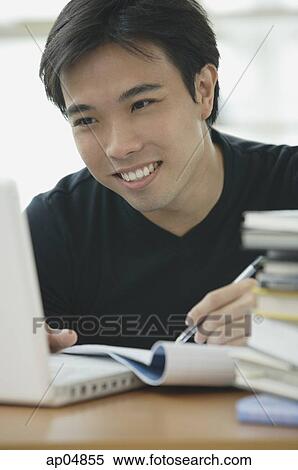 Young adult looking at laptop, writing in notebook View Large Photo Image Stock Photography - Young adult looking at laptop, writing in notebook. Fotosearch