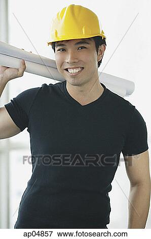 Stock Photo - Young adult wearing hardhat, carrying blueprints over his shoulder. Fotosearch