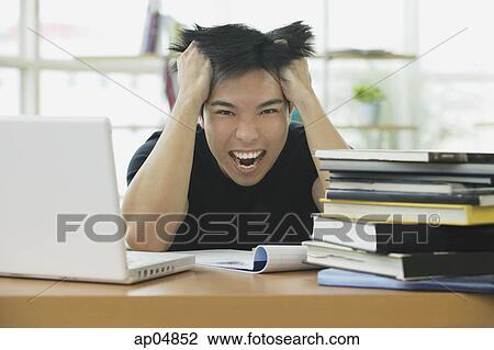 Young adult with laptop and books, hands in hair, grimacing View Large Photo Image Stock Image - Young adult with laptop and books, hands in hair, grimacing. Fotosearch