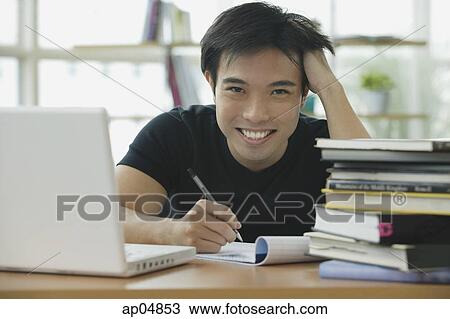 Stock Image - Young adult with laptop and books, smiling at camera. Fotosearch