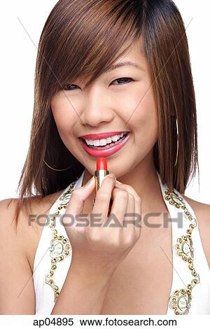Stock Photography - Young woman applying lipstick. Fotosearch