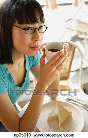 Young woman having coffee, looking away View Large Photo Image Stock Image - Young woman having coffee, looking away. Fotosearch