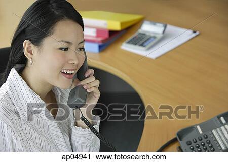 Young woman in office using telephone View Large Photo Image Stock Image - Young woman in office using telephone. Fotosearch