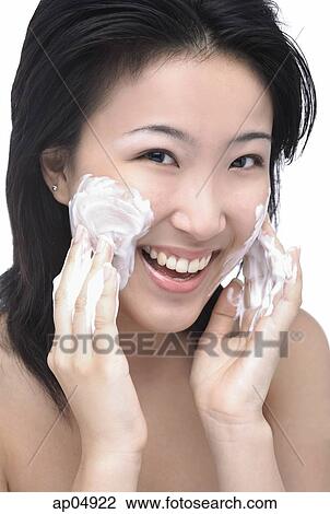 Young woman putting facial cleanser on her face, looking at camera View Large Photo Image Stock Image - Young woman putting facial cleanser on her face, looking at camera. Fotosearch