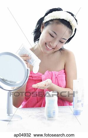 Young woman sitting at dressing table, putting moisturizer on hand View Large Photo Image Stock Image - Young woman sitting at dressing table, putting moisturizer on hand. Fotosearch